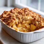 Close-up of a freshly baked apple crisp recipe with a thick, crumbly topping and soft, spiced apples underneath.