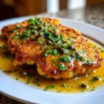 Three golden-brown, breaded chicken piccata cutlets covered in a bright lemon butter sauce with capers and fresh parsley.