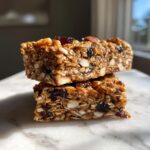 Two stacked homemade granola bars showing oats, nuts, and dried berries, perfect for a low-calorie snack.
