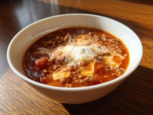 A steaming white bowl filled with rich Instant Pot Lasagna Soup topped with ricotta and Parmesan cheese.
