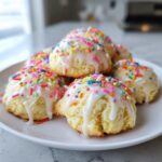 A pile of soft Italian ricotta cookies topped with white glaze and colorful sprinkles.