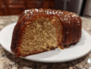 Close-up of a moist slice cut from a Bacardi Rum Cake, showing the crumb texture and rich caramel glaze dripping down.