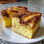 Two moist slices of classic coffee cake featuring a thick, crumbly cinnamon streusel topping on a white plate.