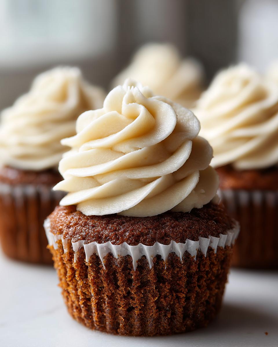 Close-up of a moist gingerbread cupcakes topped with a swirl of light cream cheese frosting.