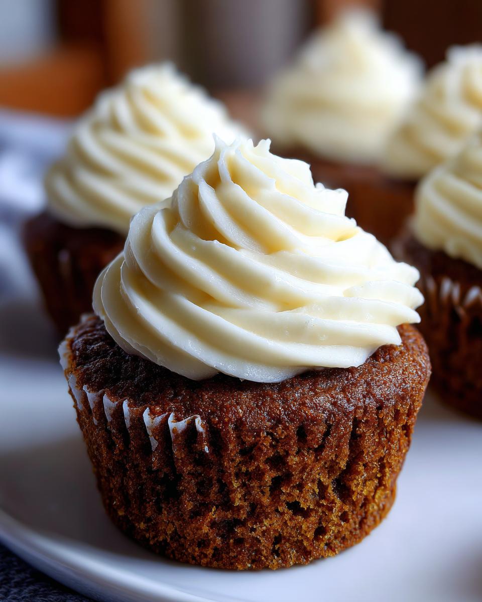 Close-up of a moist gingerbread cupcake topped with a swirl of white cream cheese frosting.