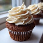 Close-up of a moist gingerbread cupcake topped with a swirl of cream cheese frosting.