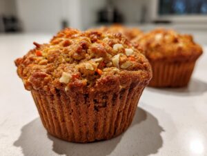 A close-up, low-angle shot of a moist morning glory muffin topped with nuts and shredded carrots.