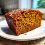 Close-up of a thick slice of moist pumpkin bread showing its rich orange color and tender crumb texture.