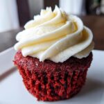 Close-up of a moist red velvet cupcakes topped with a generous swirl of white cream cheese frosting.