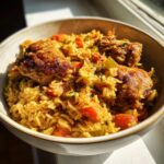 Close-up of a bowl filled with flavorful one pot chicken and rice, featuring browned chicken pieces and bright orange carrots.