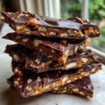 A stack of broken pieces of rich chocolate peanut butter pretzel bark showing the crunchy pretzel and peanut butter layers.