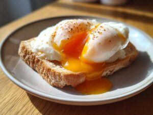 Two perfectly formed poached eggs with runny yolks spilling over seasoned toast.