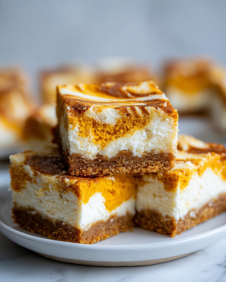 Close-up of stacked, square pumpkin cheesecake bars with a graham cracker crust and marbled orange and white filling.