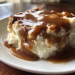 Close-up of creamy mashed potatoes generously topped with rich, brown chicken gravy.