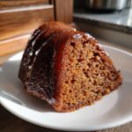 Close-up of a moist slice of Bacardi rum cake, heavily glazed and sitting on a white plate.