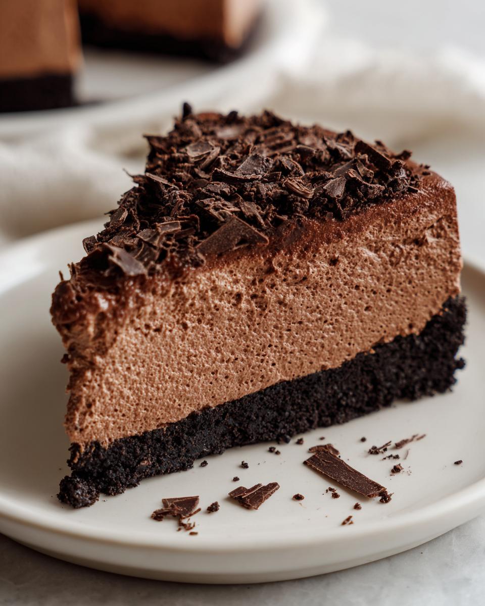 A perfect slice of chocolate mousse pie showing a thick, airy filling over a dark crust, topped with chocolate shavings.