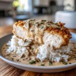 A cross-section view of crispy smothered chicken and rice topped with creamy mushroom gravy.