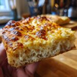 Close-up of a thick slice of cheesy bread made from sourdough discard pizza dough showing an airy interior.