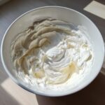 A white bowl filled with stiff, perfectly mixed gingerbread house icing, ready for decorating.