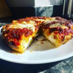 Close-up of a thick-crust homemade pizza slice removed, showing fluffy dough, melted mozzarella, and bright red sauce.